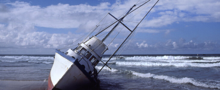 A fishing boat lists as it sits grounded in the surf.