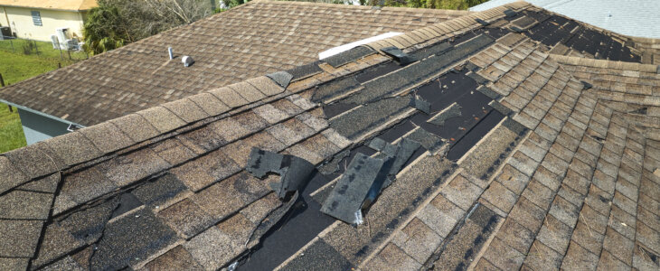 Wind damaged house roof with missing asphalt shingles after hurricane Idalia in Florida. Repair of home rooftop concept.