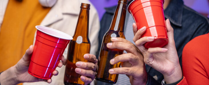 Close up group friends celebrating with beer bottles and clinking on party. Home party friends having fun enjoying time and dancing together. New Year's Eve Party concept